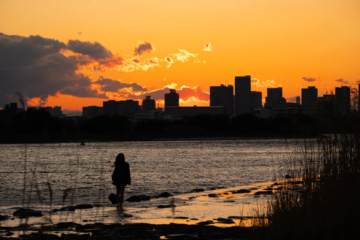 Orange sunset over a Tokyo skyline and waterfront.